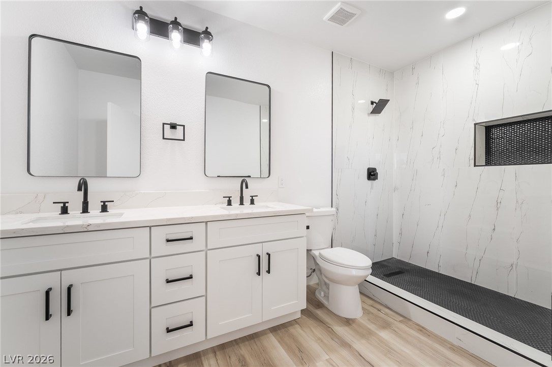39 Lowery Street Henderson, NV 89015 - Photo 18 of 40 A well-lit primary bathroom featuring dual vanities, modern fixtures, and a spacious walk-in shower.