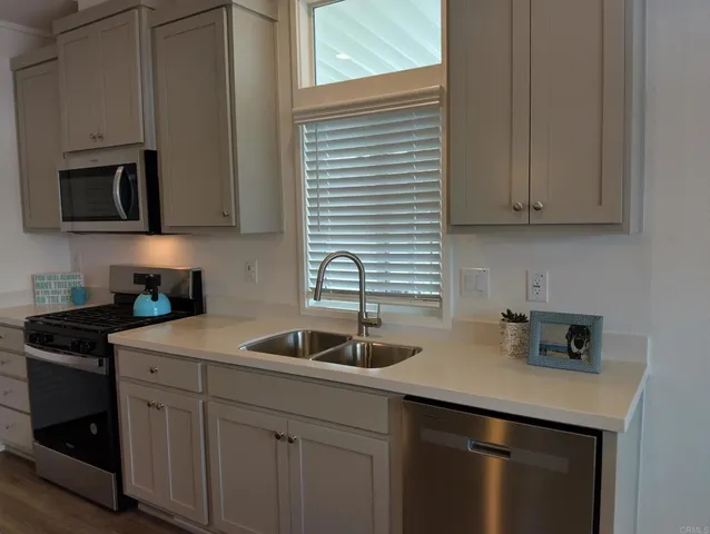 a kitchen with stainless steel appliances granite countertop a sink a stove and a microwave