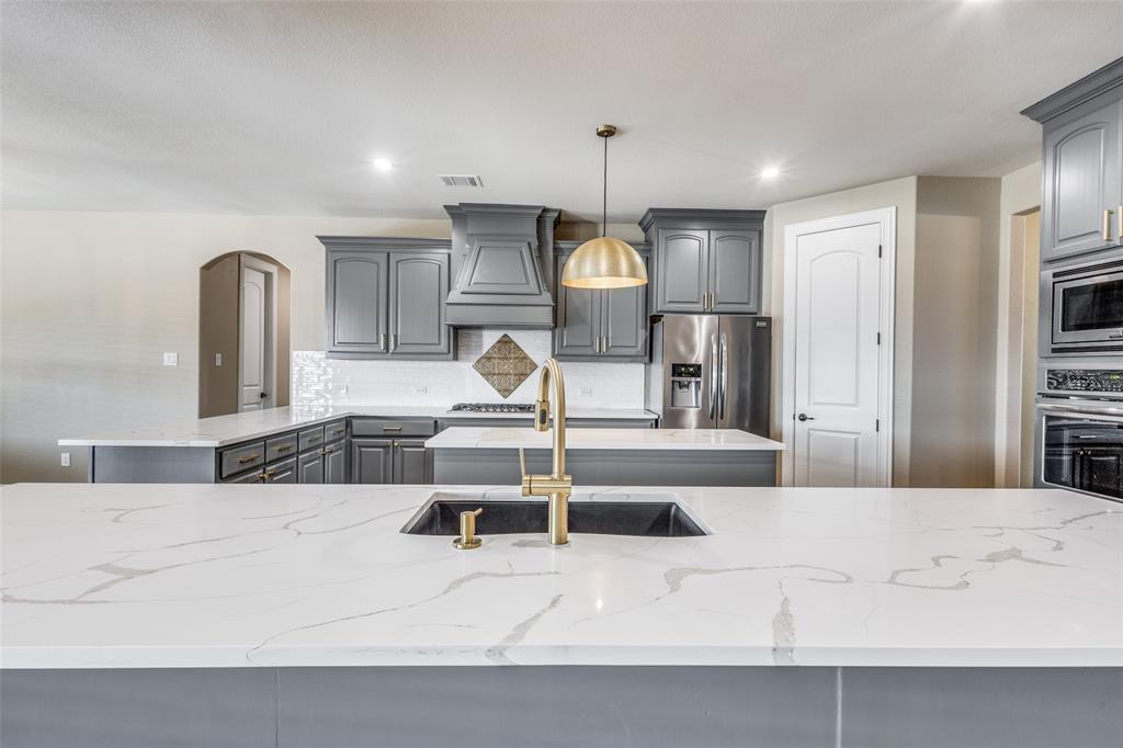 2143 Canyon Road Celina, TX 75009 - Photo 21 of 39 a large kitchen with stainless steel appliances kitchen island granite countertop a sink and a refrigerator