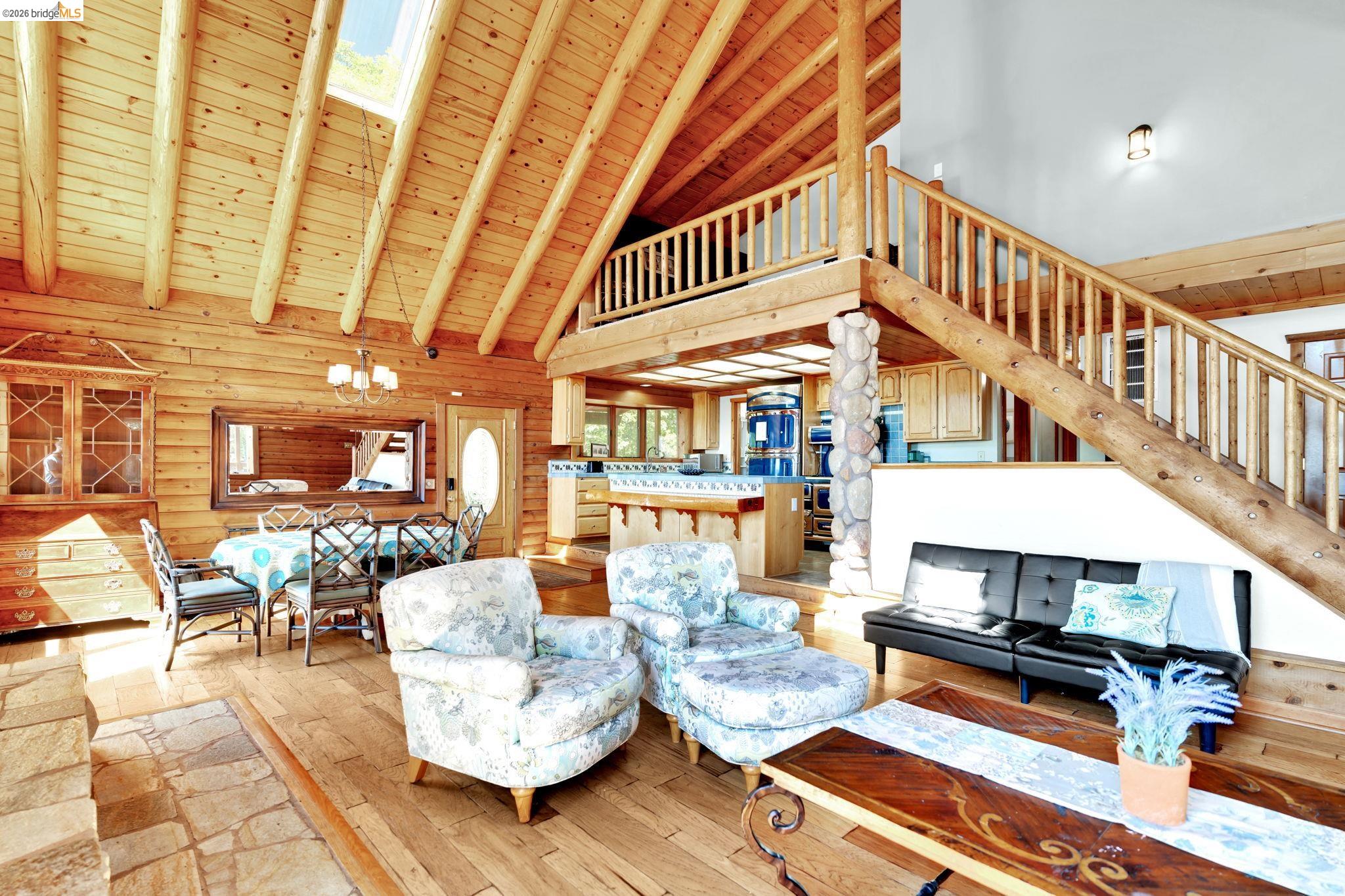 14799 Big Hill Road Sonora, CA 95370 - Photo 13 of 60 Living area featuring a high wooden beamed ceiling, a chandelier, light wood-style flooring, log walls, and a skylight