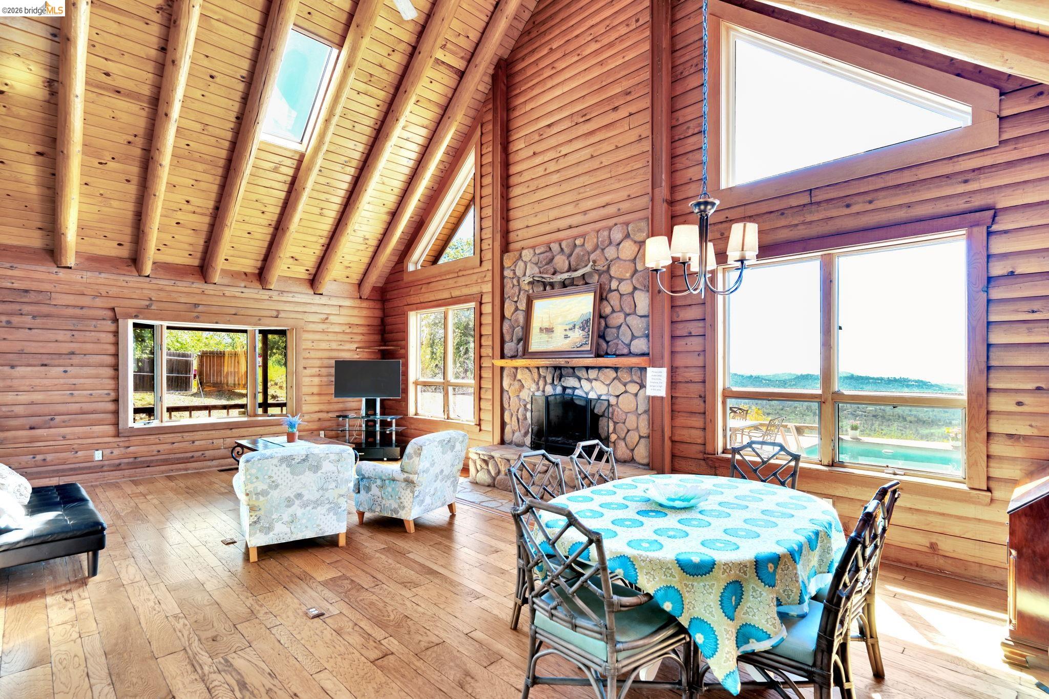 14799 Big Hill Road Sonora, CA 95370 - Photo 14 of 60 Dining space with a skylight, hardwood / wood-style flooring, a fireplace, suspended lighting, and a high wooden beamed ceiling