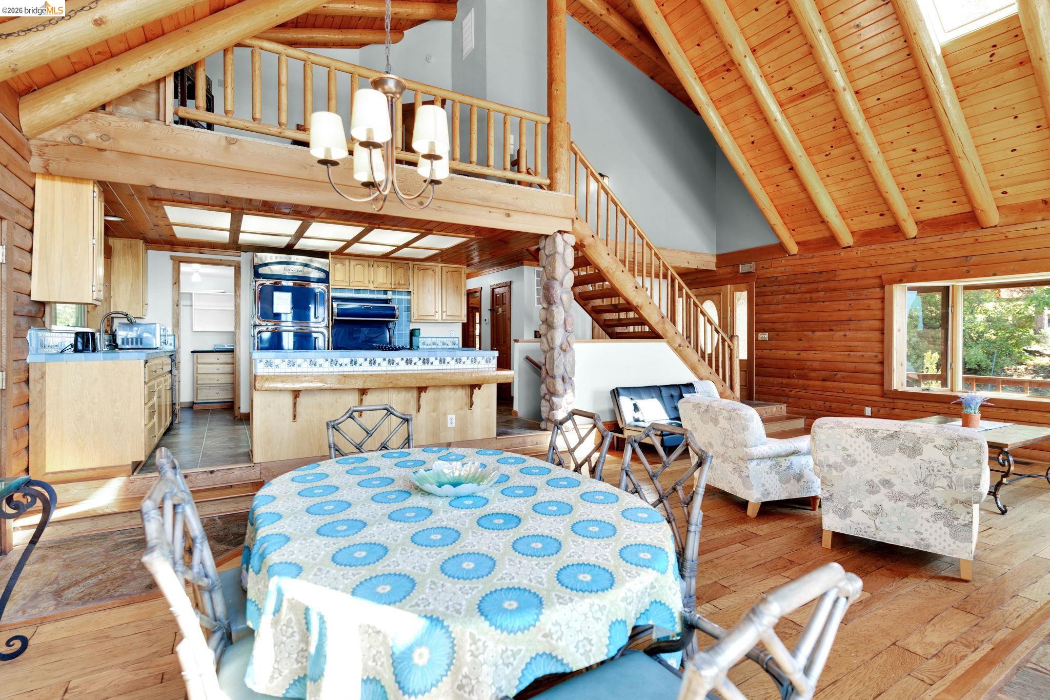 14799 Big Hill Road Sonora, CA 95370 - Photo 15 of 60 Dining area with a high wooden beamed ceiling, light wood-style floors, suspended lighting, rustic walls, and a skylight