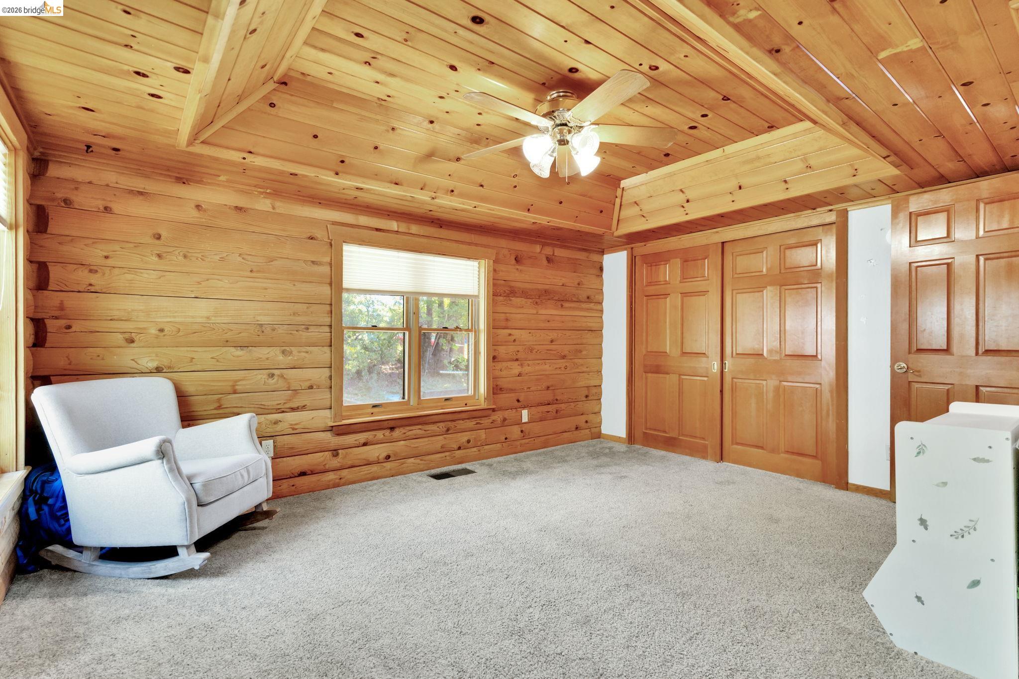 14799 Big Hill Road Sonora, CA 95370 - Photo 23 of 60 Unfurnished room featuring a wood tray ceiling, carpet floors, wooden walls, and ceiling fan