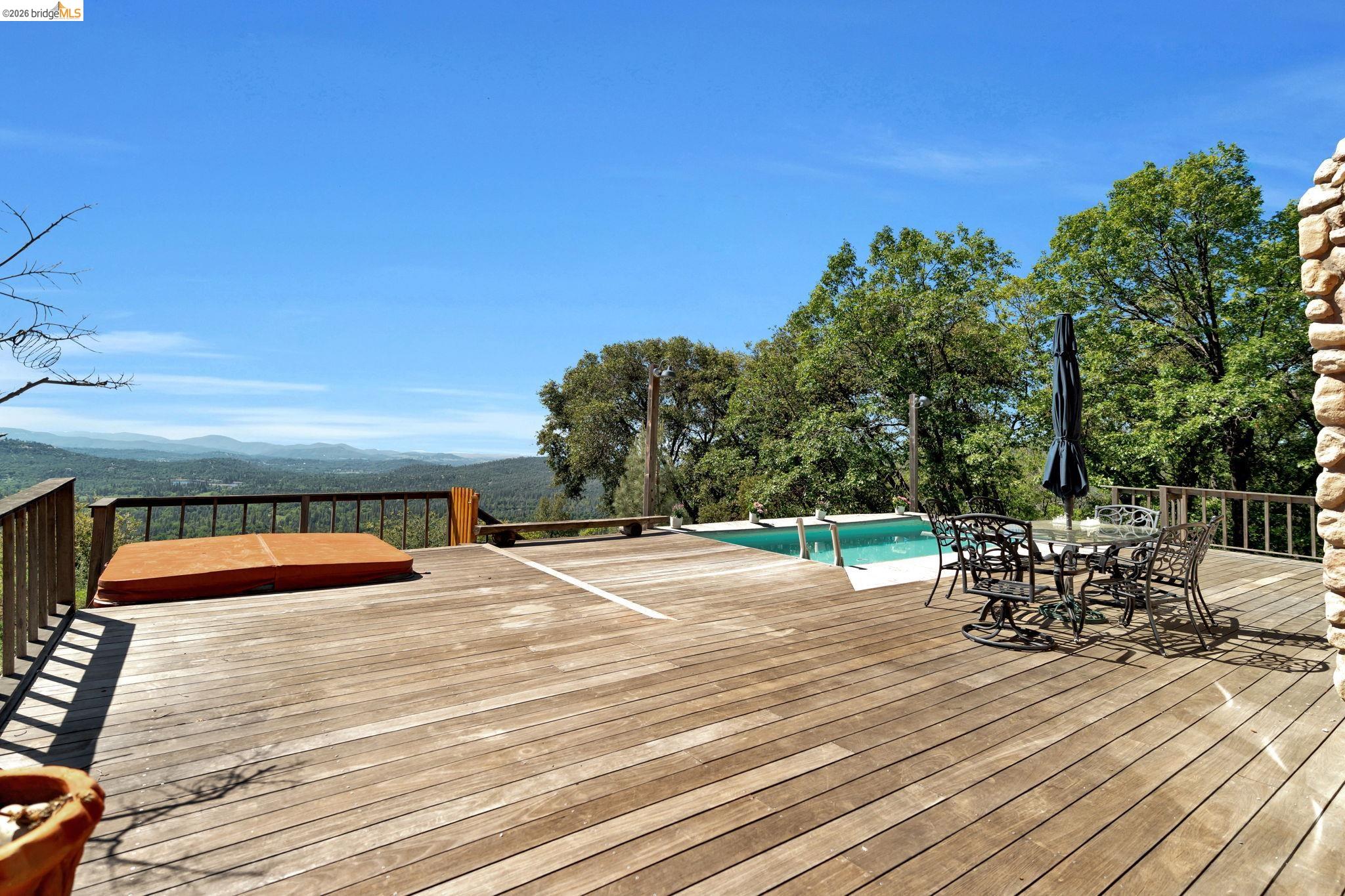 14799 Big Hill Road Sonora, CA 95370 - Photo 36 of 60 Deck with an outdoor pool, outdoor dining space, and a mountain view