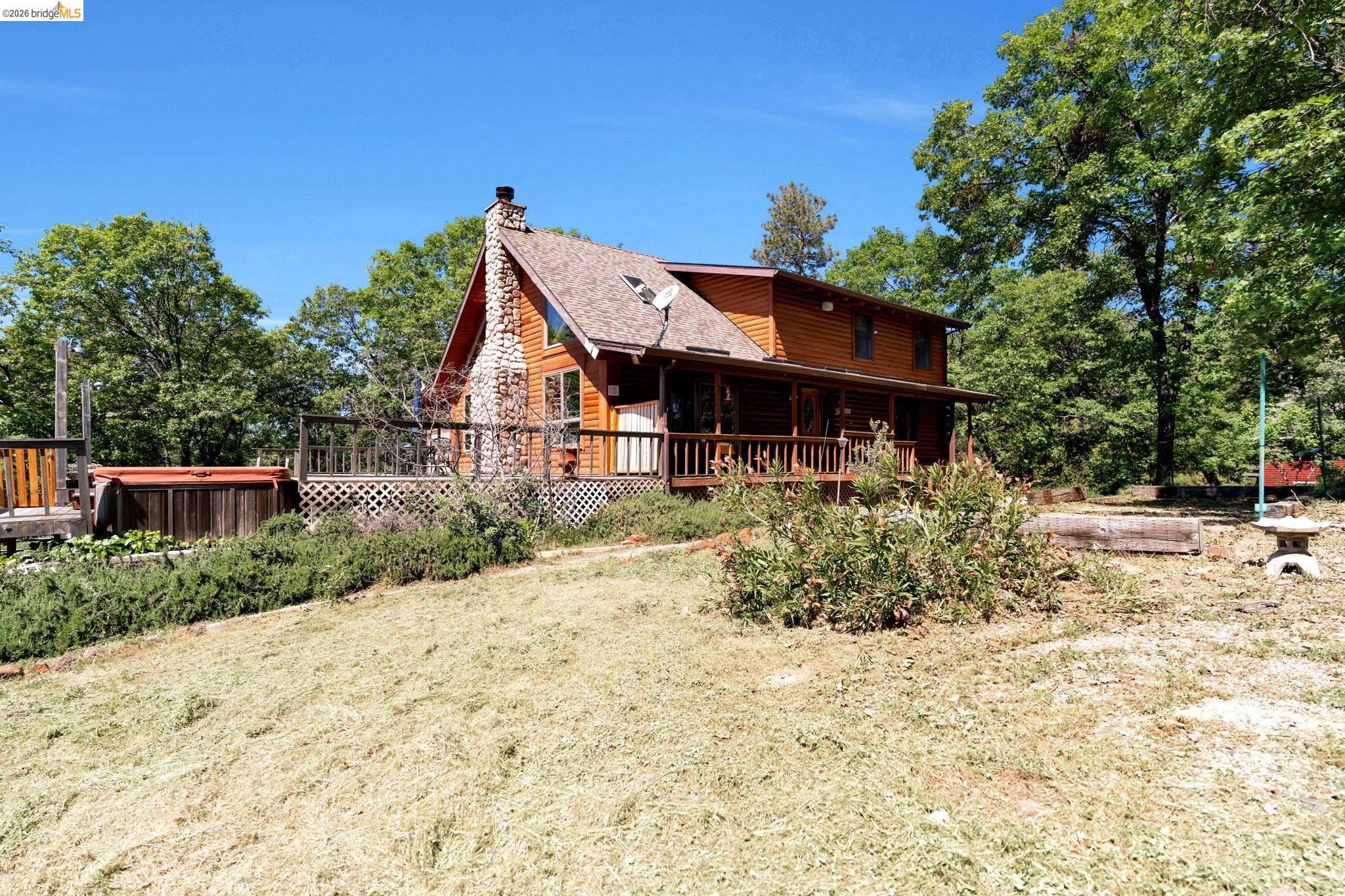 14799 Big Hill Road Sonora, CA 95370 - Photo 42 of 60 Back of house featuring a chimney, a hot tub, a wooden deck, and a yard