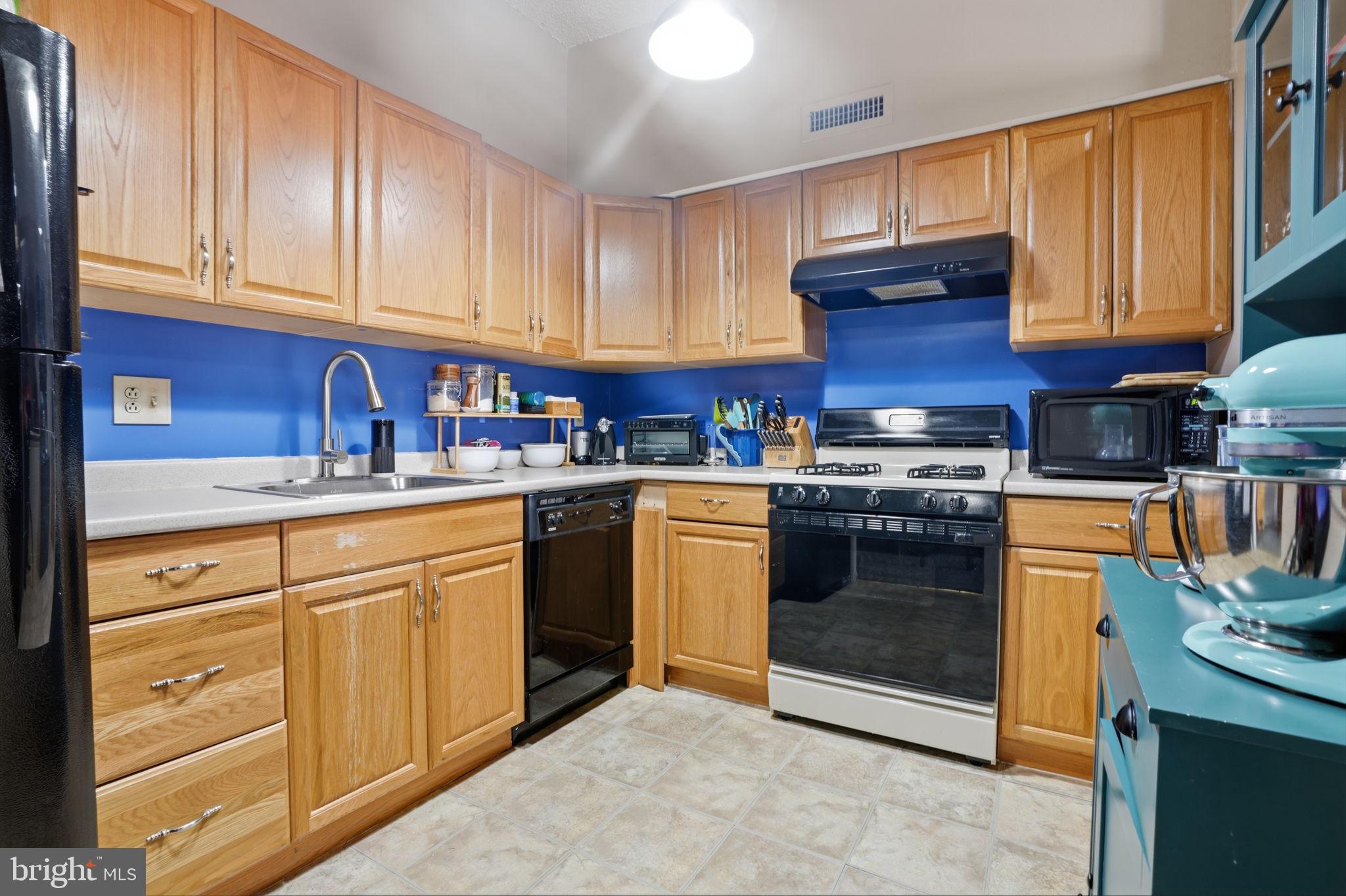 62204 Delaire Landing Road, Unit 204 Philadelphia, PA 19114 - Photo 10 of 35 a kitchen with stainless steel appliances granite countertop a stove top oven a sink dishwasher and cabinets with wooden floor