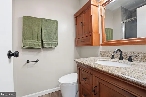 a bathroom with a granite countertop sink a toilet and a mirror