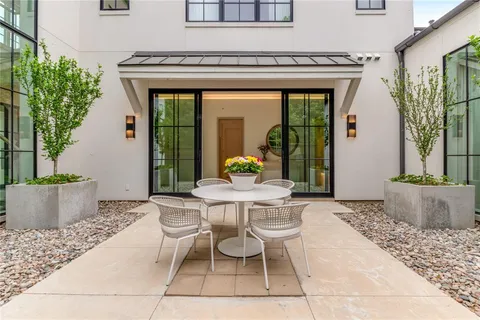 a view of a patio with table and chairs potted plants and floor to ceiling window and potted plants