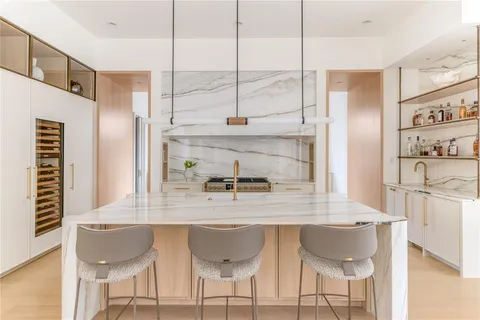 a kitchen with a dining table chairs and white cabinets next to a window