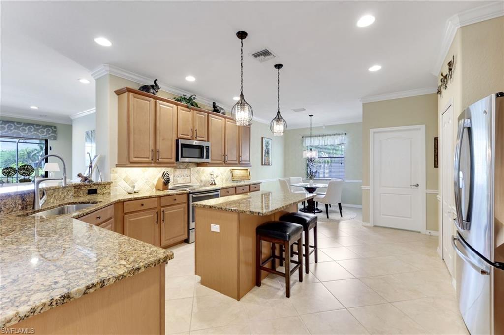 3917 Sapphire Way Naples, FL 34114 - Photo 9 of 44 a kitchen with stainless steel appliances granite countertop sink refrigerator and cabinets