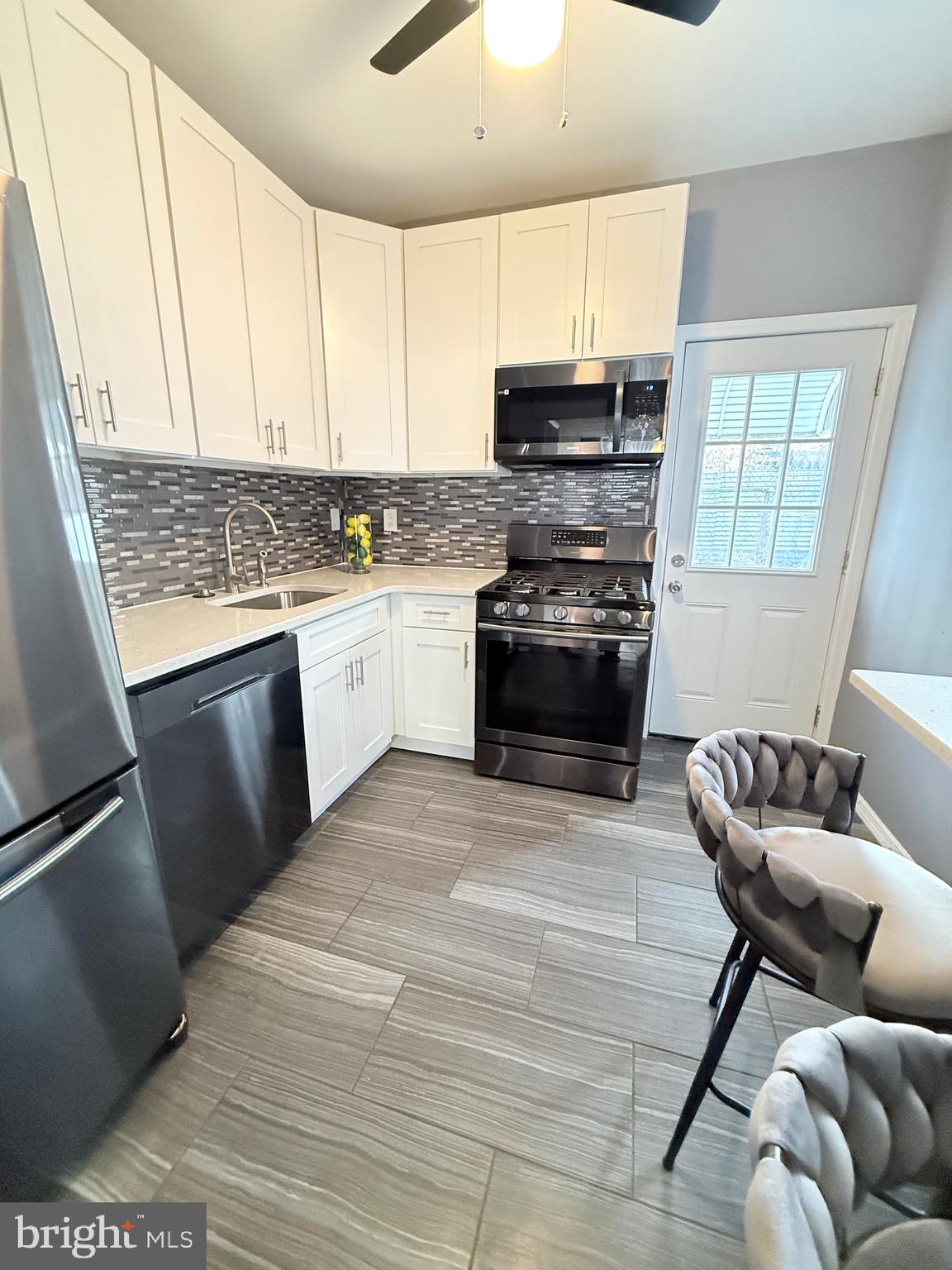 3146 Mercer Street Philadelphia, PA 19134 - Photo 9 of 22 a kitchen with stainless steel appliances granite countertop a stove top oven a sink dishwasher a dining table and chairs with wooden floor