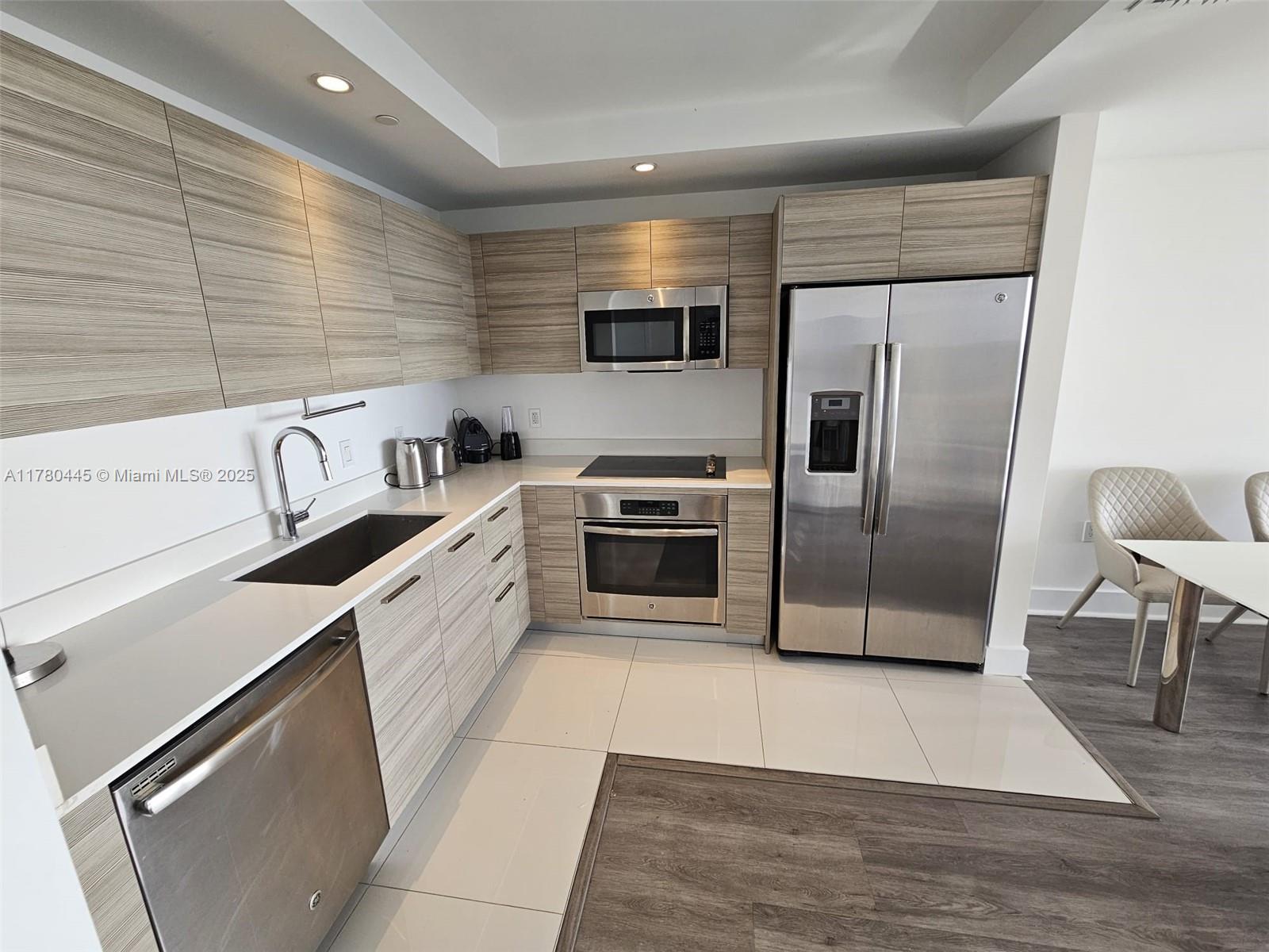 121 Northeast 34th Street, Unit 2511 Miami, FL 33137 - Photo 1 of 46 a kitchen with granite countertop a refrigerator and a stove top oven