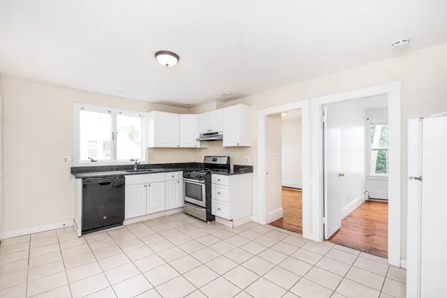 a kitchen with granite countertop a refrigerator and white cabinets