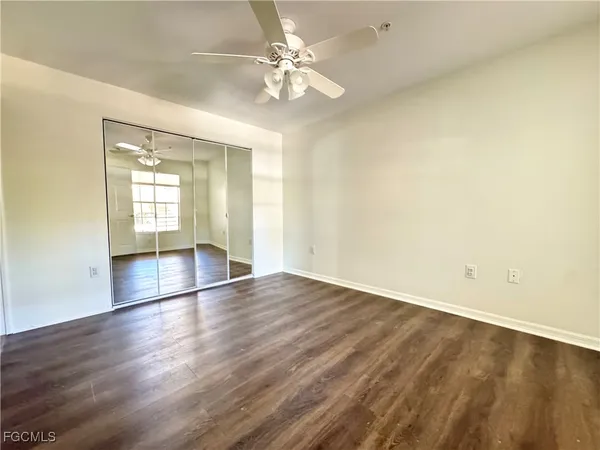 an empty room with wooden floor and fan