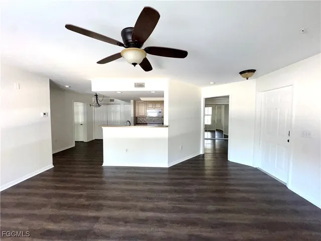 a view of a livingroom with a ceiling fan wooden floor and a ceiling fan