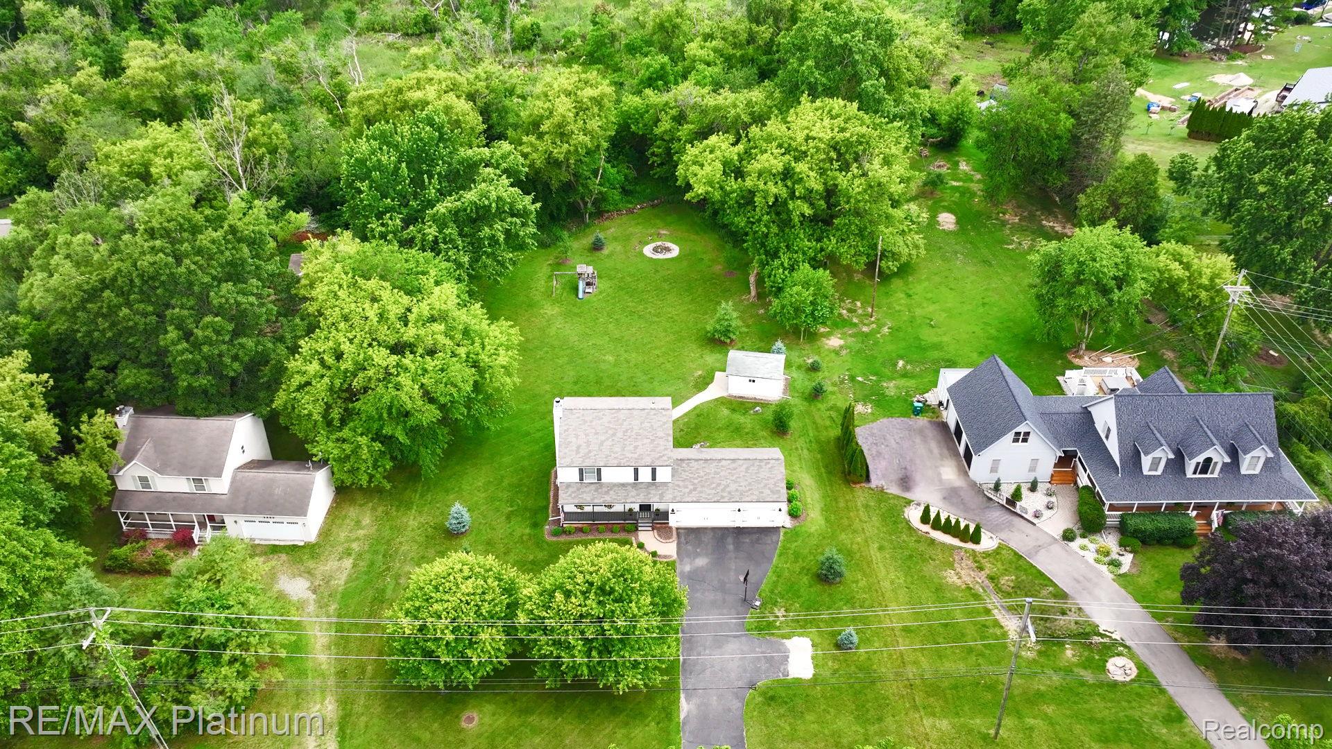 2401 Golf Club Road Howell, MI 48843 - Photo 5 of 8 Spacious property featuring multiple dwellings, extensive green lawns, mature trees, and a paved driveway