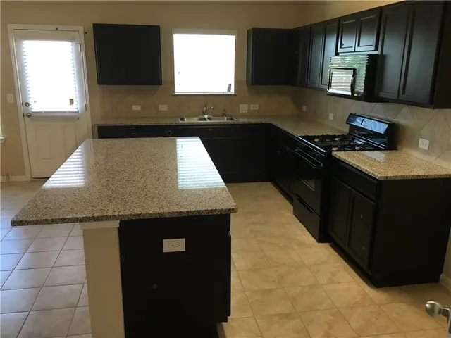 a kitchen with granite countertop stainless steel appliances a sink stove top oven and granite counter tops