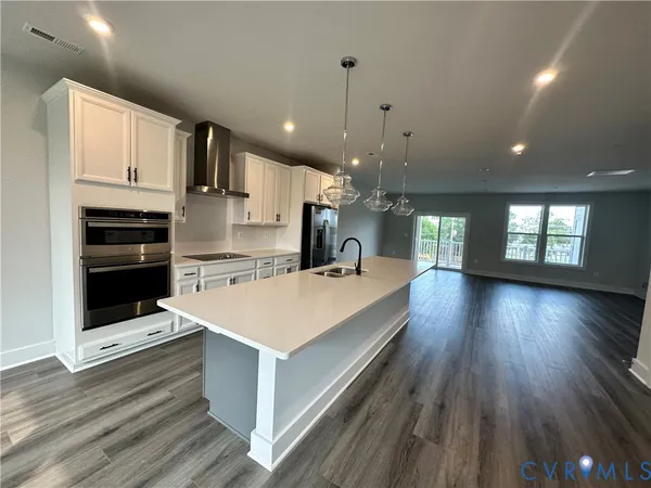 a large kitchen with kitchen island a stove a sink dishwasher and a refrigerator with wooden floor