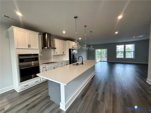 a large kitchen with stainless steel appliances a large counter top a sink a stove and a refrigerator