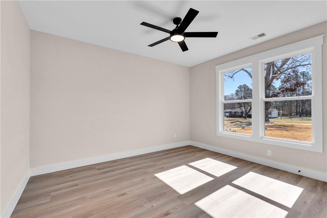 2816 Smith McGee Road Iva, SC 29655 - Photo 21 of 25 A well-lit room showcasing rich hardwood flooring, a contemporary ceiling fan, and views of the surrounding natural landscape.
