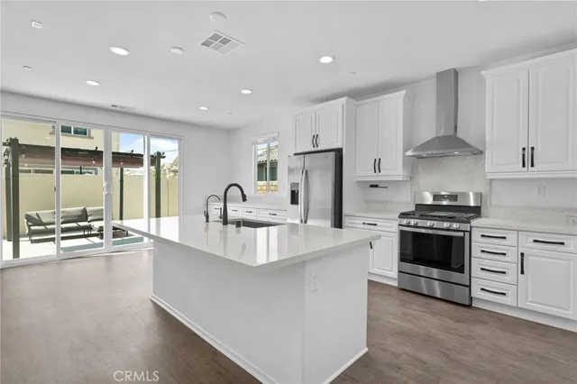 a large white kitchen with stainless steel appliances granite countertop a stove and a sink