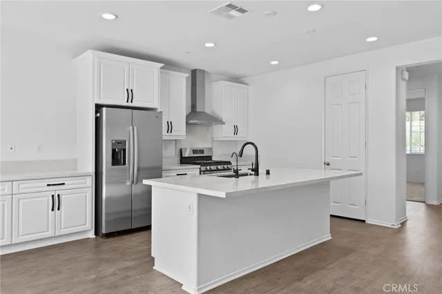 a kitchen with stainless steel appliances a refrigerator sink and white cabinets