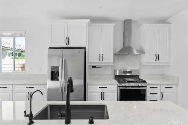 a kitchen with stainless steel appliances granite countertop a stove a refrigerator and a sink with wooden floor