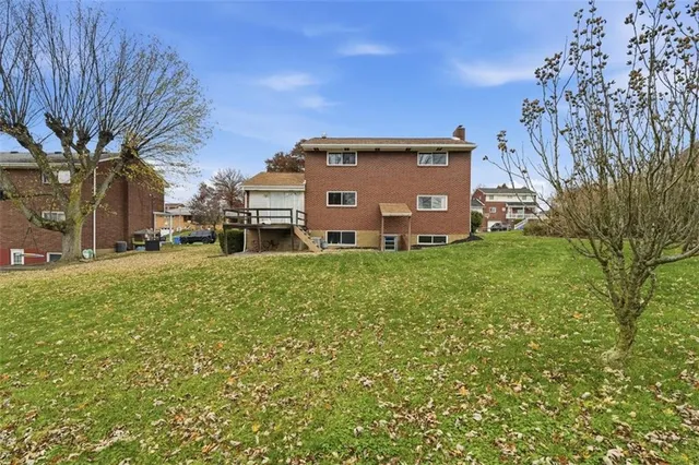 a view of a house with a big yard and large trees
