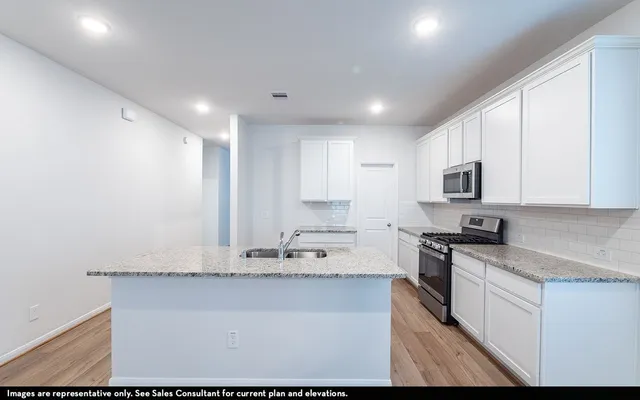 a kitchen with granite countertop white cabinets and stainless steel appliances