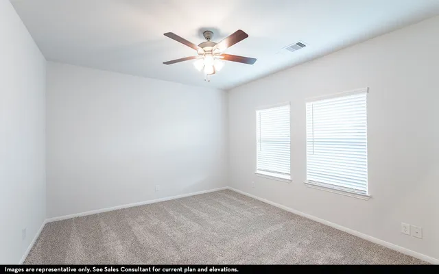 an empty room with windows and ceiling fan