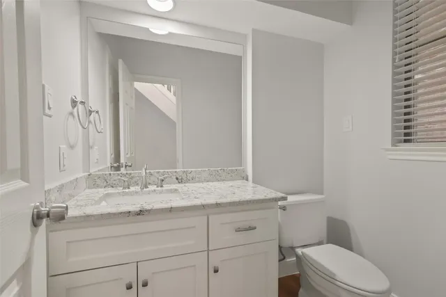 a bathroom with a granite countertop toilet sink and mirror