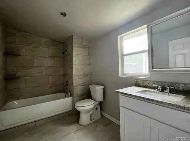 a bathroom with a granite countertop toilet a sink and bathtub