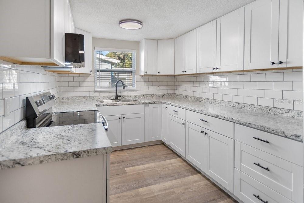 7605 Fox Hollow Drive Port Richey, FL 34668 - Photo 11 of 29 a kitchen with granite countertop a sink dishwasher stove and cabinets