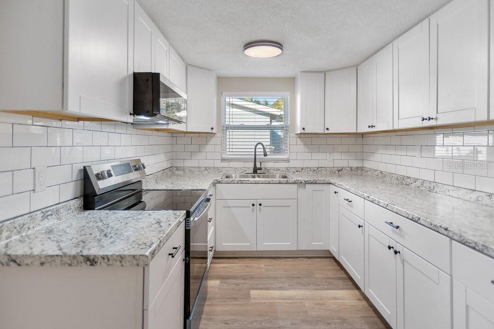 7605 Fox Hollow Drive Port Richey, FL 34668 - Photo 12 of 29 a kitchen with granite countertop a sink dishwasher stove and cabinets