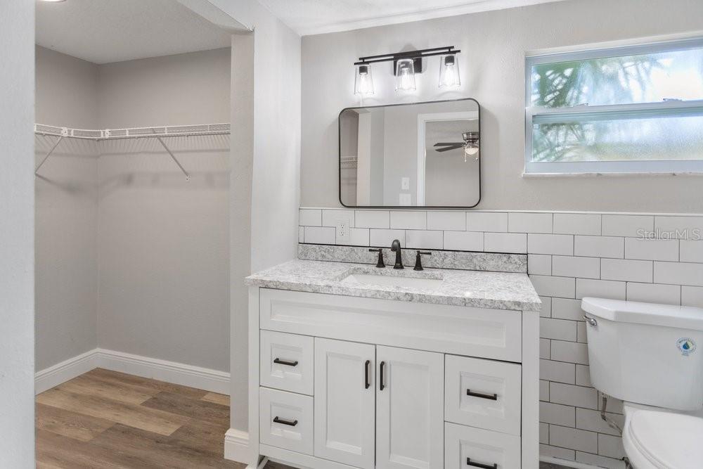 7605 Fox Hollow Drive Port Richey, FL 34668 - Photo 20 of 29 a bathroom with a granite countertop sink a toilet and a mirror