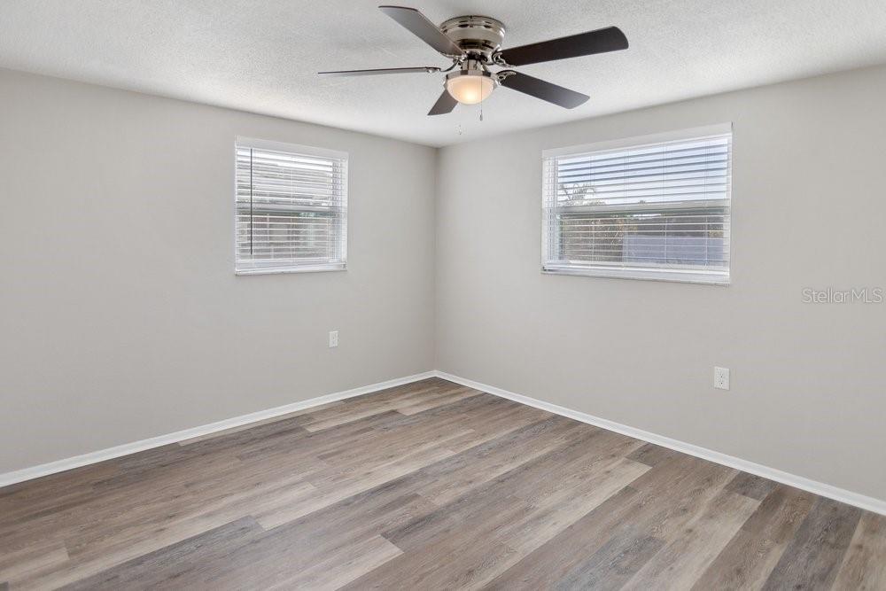 7605 Fox Hollow Drive Port Richey, FL 34668 - Photo 9 of 29 an empty room with wooden floor ceiling fan and windows