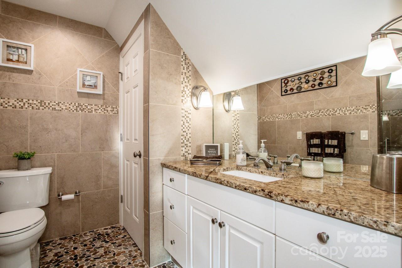 570 Morrison Farm Road Troutman, NC 28166 - Photo 25 of 32 a bathroom with a granite countertop sink a toilet a mirror and shower