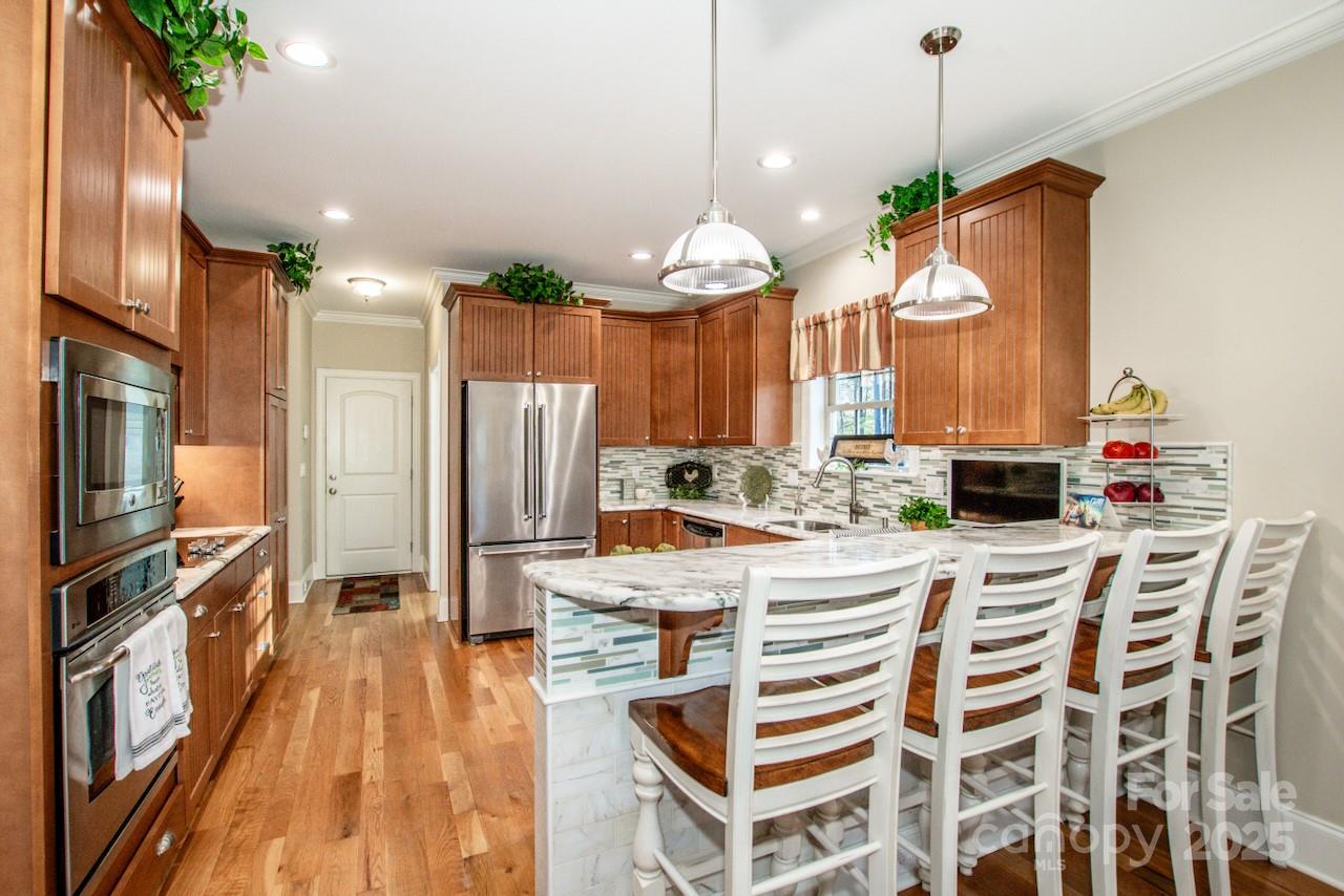 570 Morrison Farm Road Troutman, NC 28166 - Photo 8 of 32 a kitchen with stainless steel appliances granite countertop a refrigerator a sink dishwasher a oven and a dining table with wooden floor