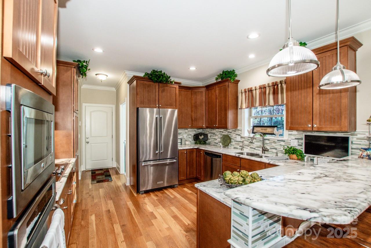 570 Morrison Farm Road Troutman, NC 28166 - Photo 10 of 32 a kitchen with stainless steel appliances kitchen island granite countertop a refrigerator a oven a sink with island and chairs