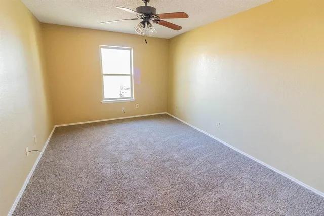 an empty room with a window and a fan