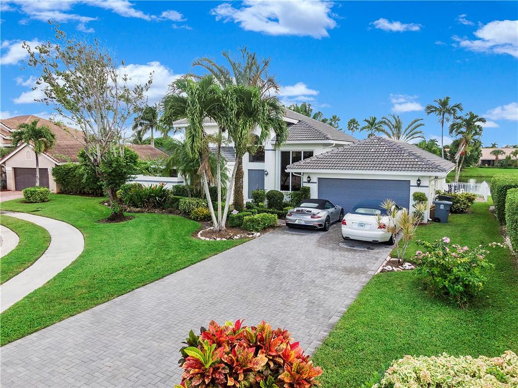 9695 West Lake Court Boca Raton, FL 33434 - Photo 2 of 43 a front view of a house with a garden and a yard