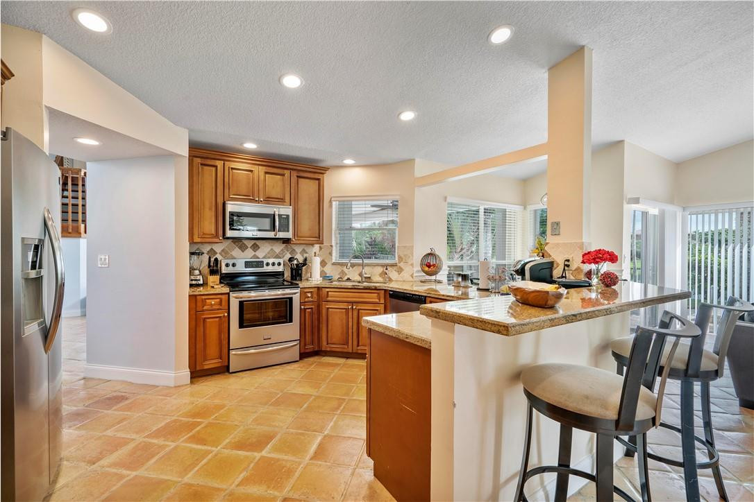 9695 West Lake Court Boca Raton, FL 33434 - Photo 8 of 43 a kitchen with stainless steel appliances kitchen island granite countertop a sink and cabinets