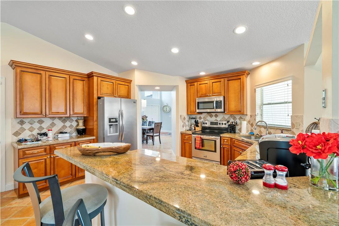 9695 West Lake Court Boca Raton, FL 33434 - Photo 9 of 43 a kitchen with stainless steel appliances kitchen island granite countertop a stove and cabinets