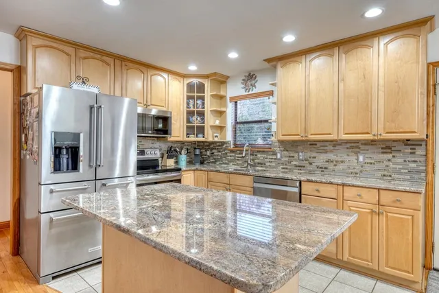 a kitchen with stainless steel appliances granite countertop a refrigerator a stove top oven a sink dishwasher and white cabinets with wooden floor