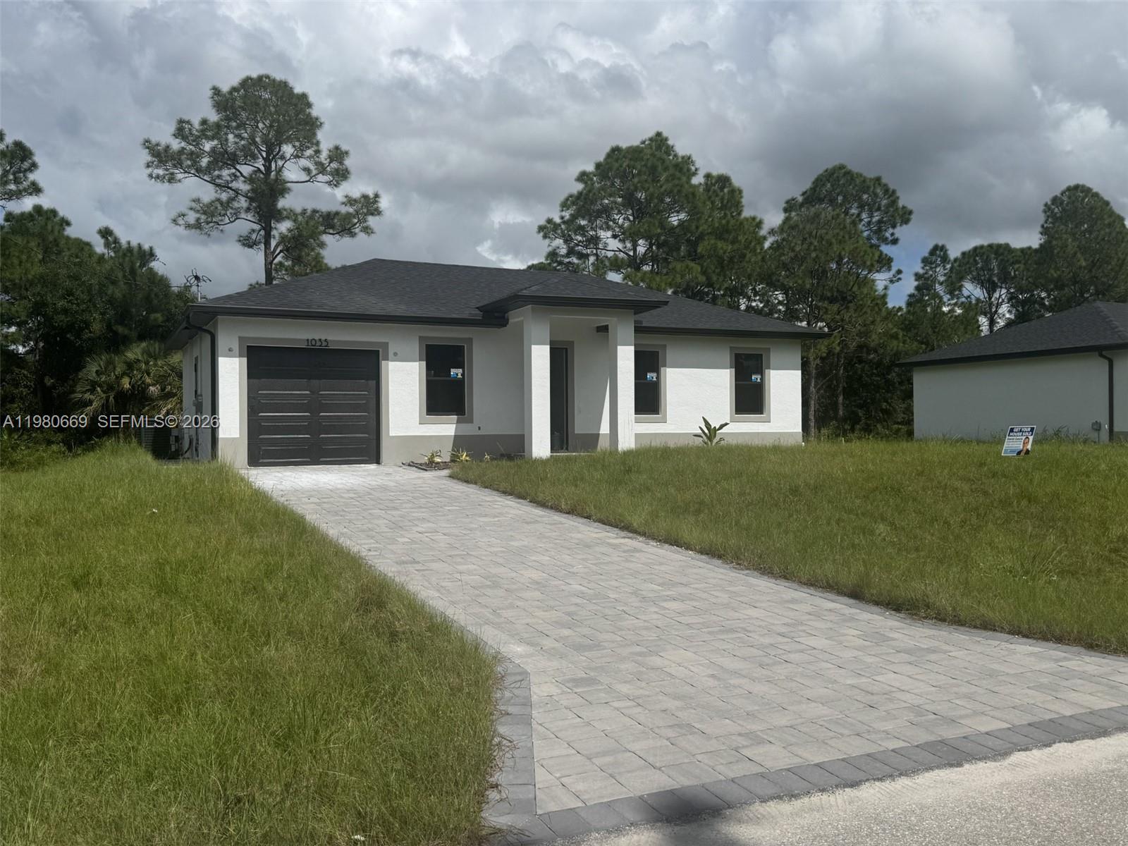 1127 Chipley Street Lehigh Acres, FL 33974 - Photo 1 of 1 a front view of a house with a yard and a garage