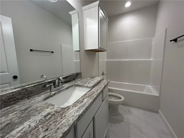 a bathroom with a granite countertop sink a toilet and a bathtub