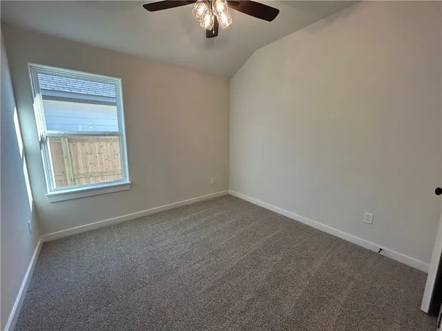 an empty room with a chandelier fan and windows