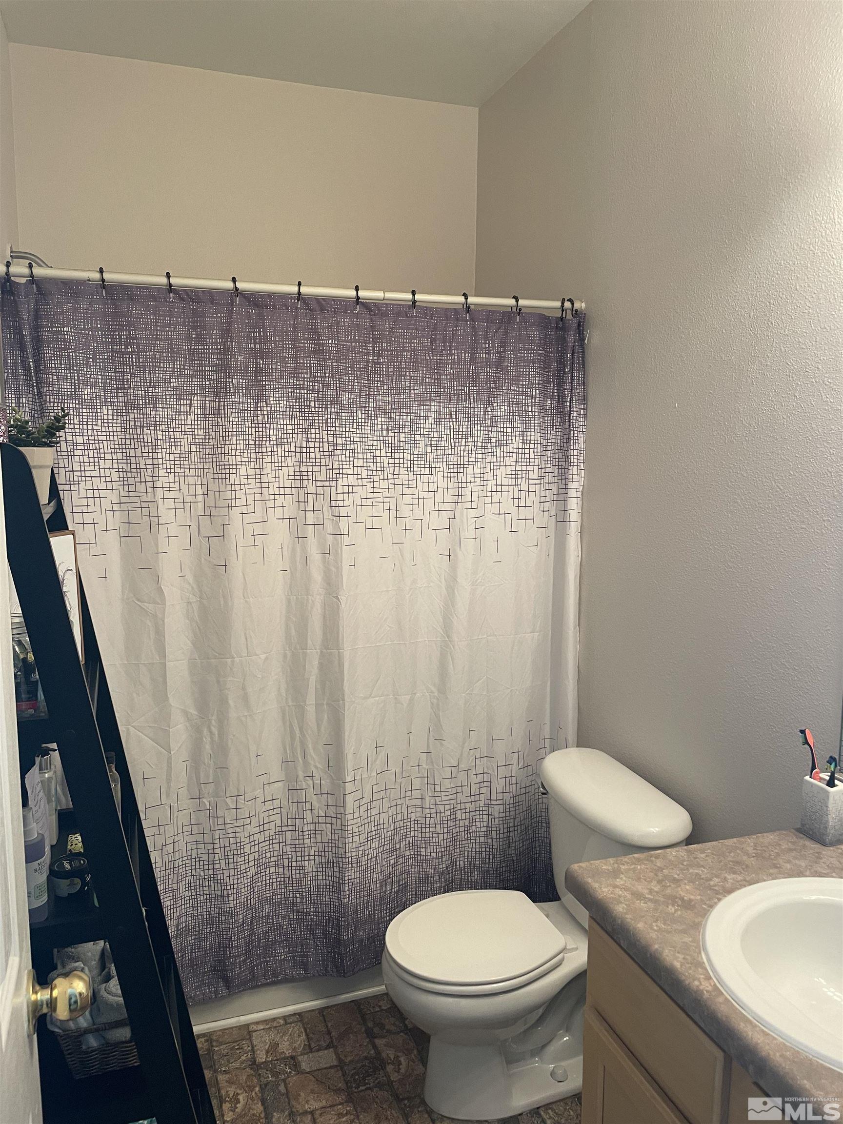 200 Talus Way, Unit 421 Reno, NV 89503 - Photo 17 of 23 a bathroom with a granite countertop sink a toilet a mirror and shower curtain