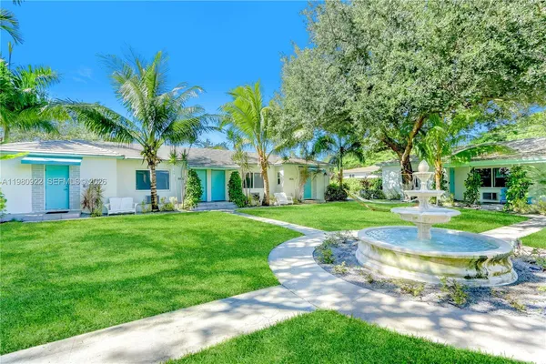 a view of a house with a big yard plants and large trees