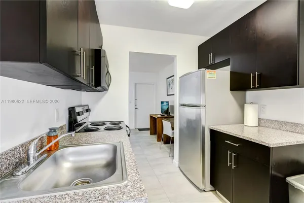 a kitchen with stainless steel appliances granite countertop a sink a stove a refrigerator a washer and dryer